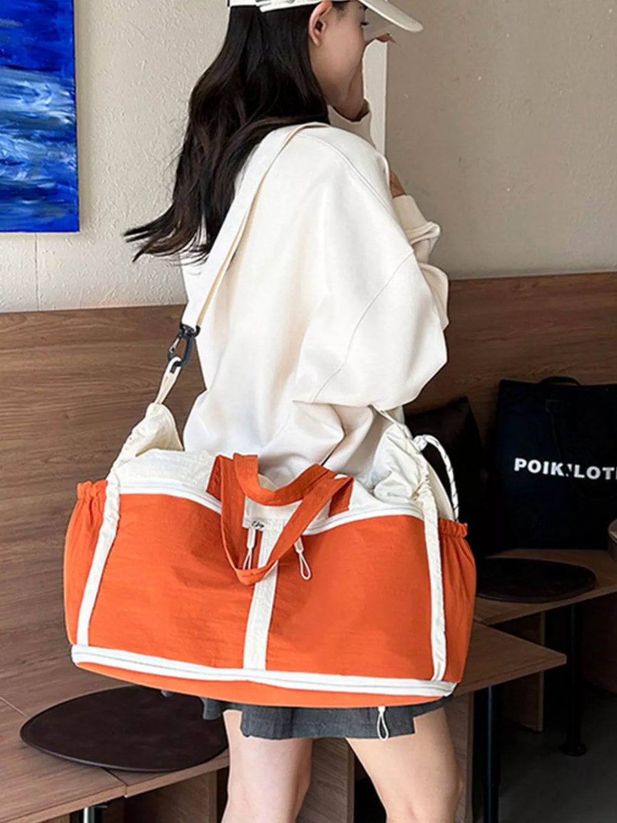 Person carrying an orange and white duffel bag in a casual setting.