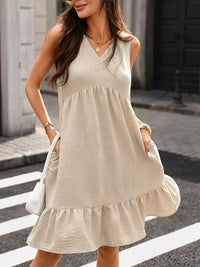 Woman wearing a beige sleeveless dress crossing a street.