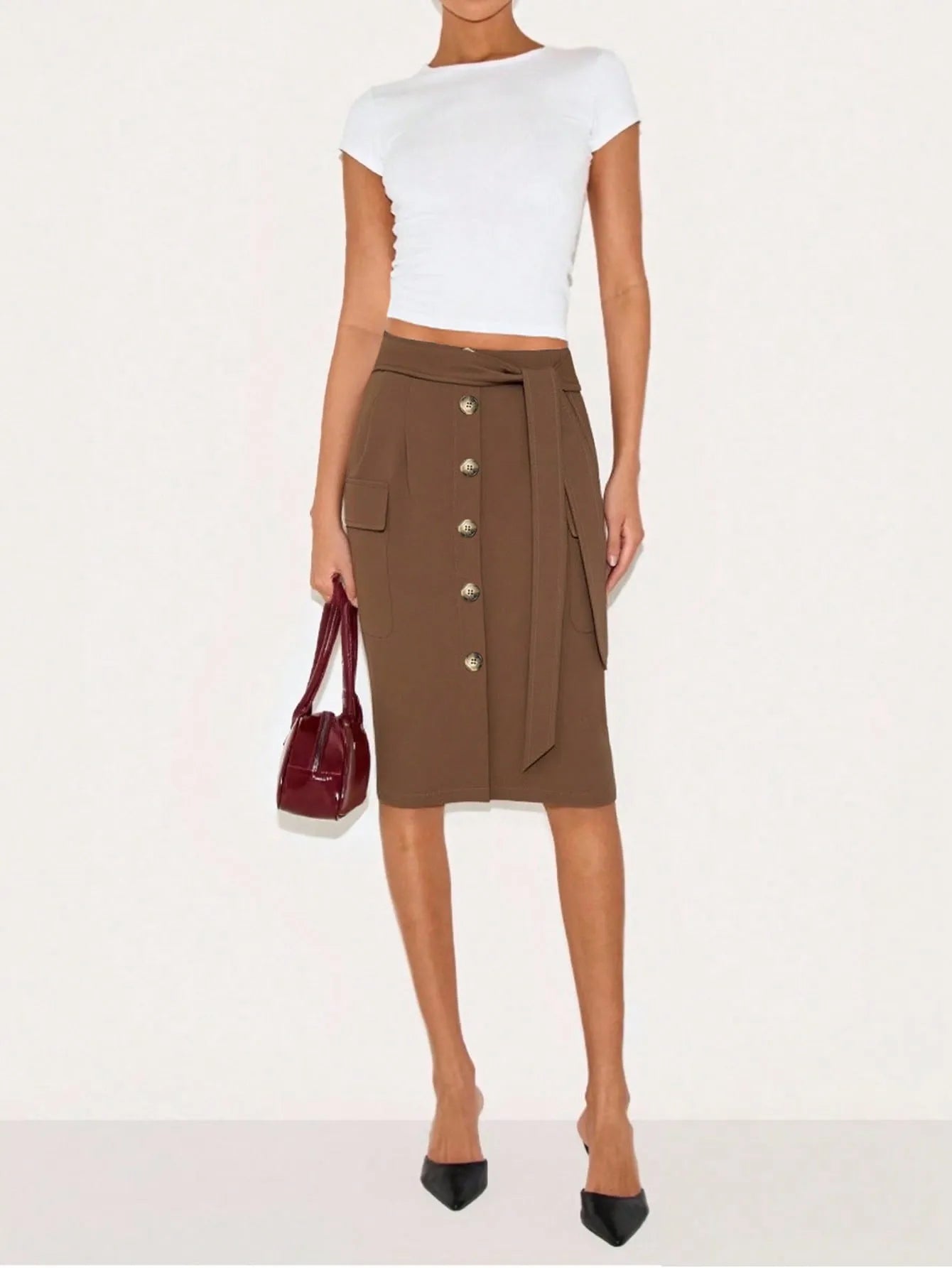 Person wearing a brown button-up skirt with a white top on a white background