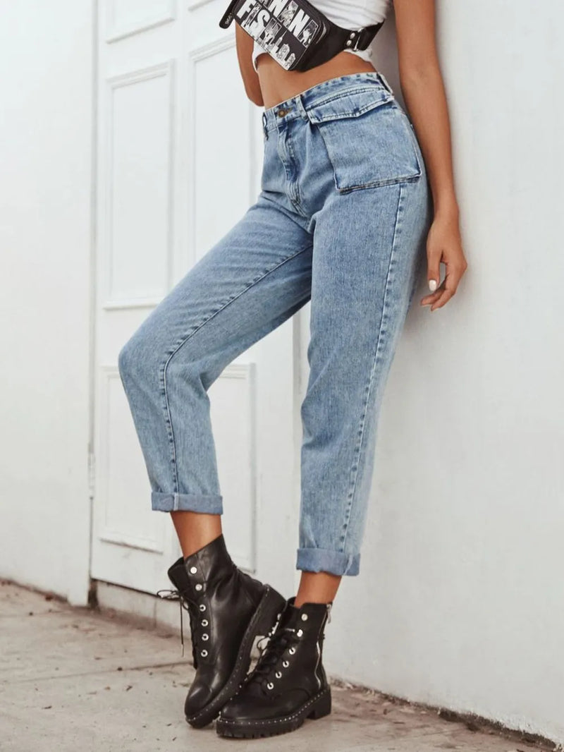 Person wearing blue jeans and black combat boots against a white wall.