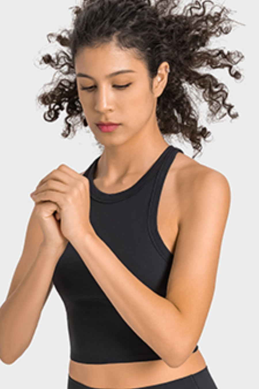 Woman wearing a black sports bra on a light gray background
