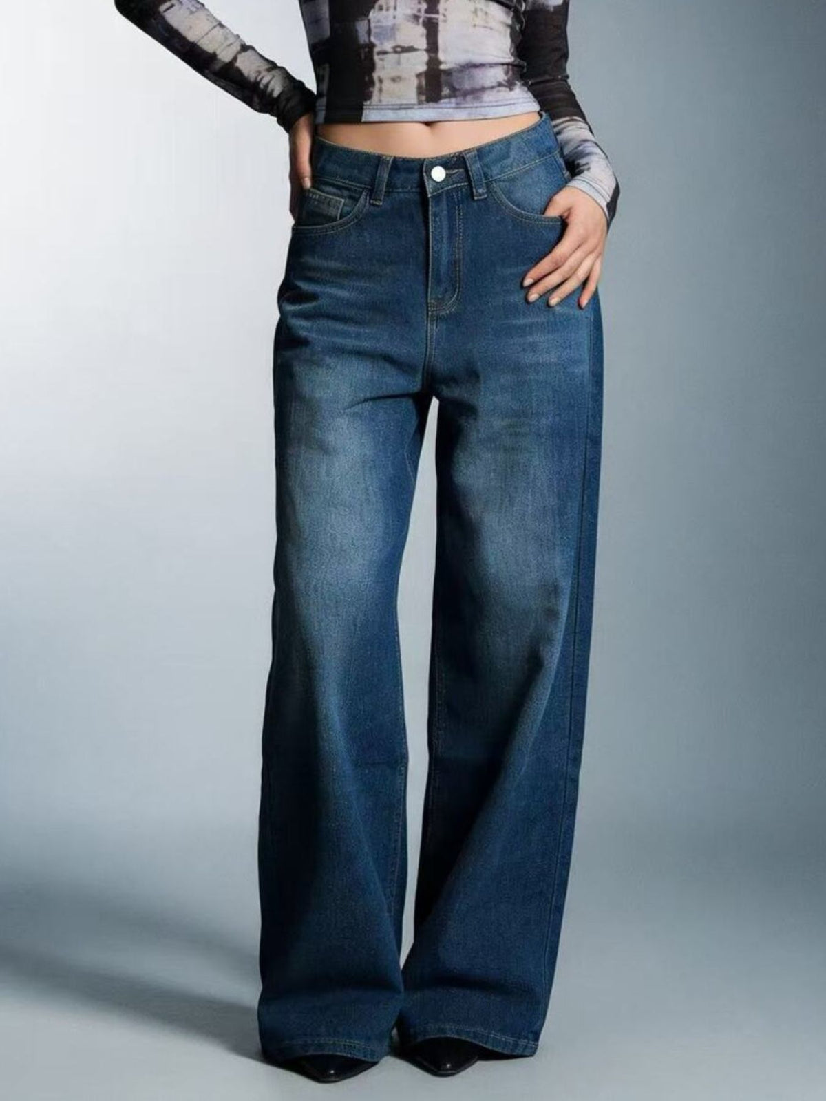 Person wearing blue wide-leg jeans on a gray background