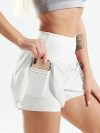 Person wearing white athletic shorts with a pocket, holding a phone.