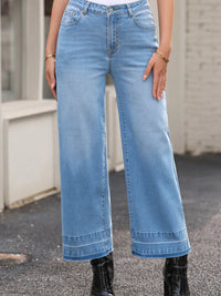 Person wearing light blue wide-leg jeans with a blurred background