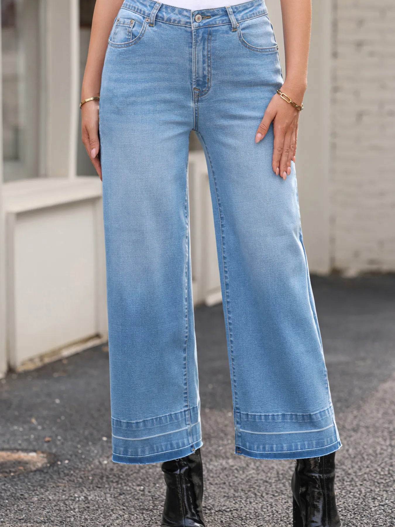 Person wearing light blue wide-leg jeans with a blurred background