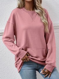 Person wearing a pink sweatshirt with a neutral background