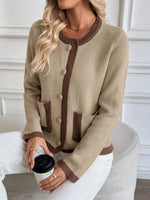 Woman wearing a beige sweater with brown accents, sitting on a white chair.