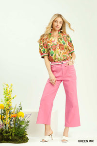 Woman wearing a colorful shirt and pink pants with a white background