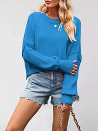 Person wearing a blue sweater and denim shorts on a plain background
