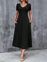 Woman wearing a black dress against a gray concrete wall.