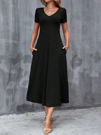 Woman wearing a black dress against a gray concrete wall.