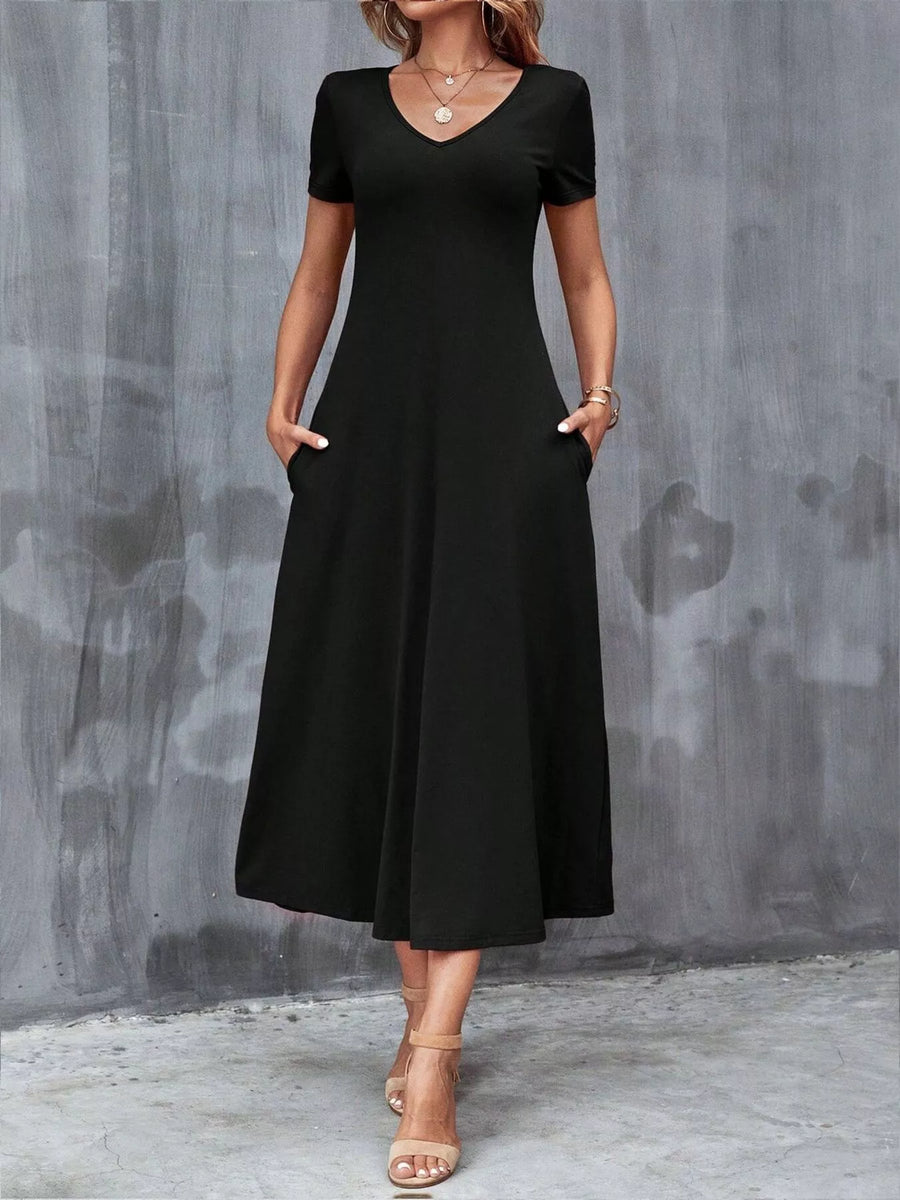 Woman wearing a black dress against a gray concrete wall.