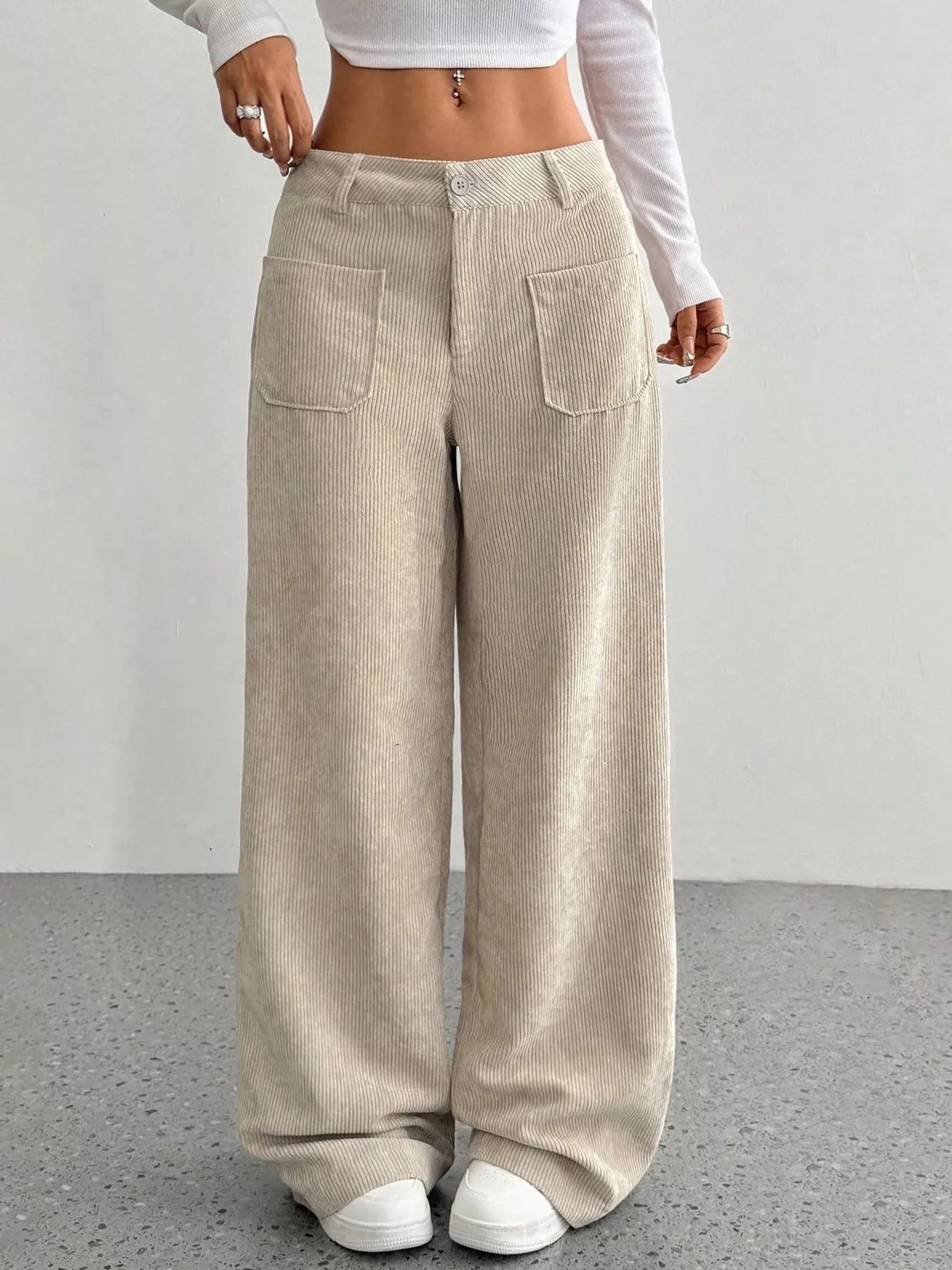 Person wearing beige corduroy wide-leg pants on a plain background