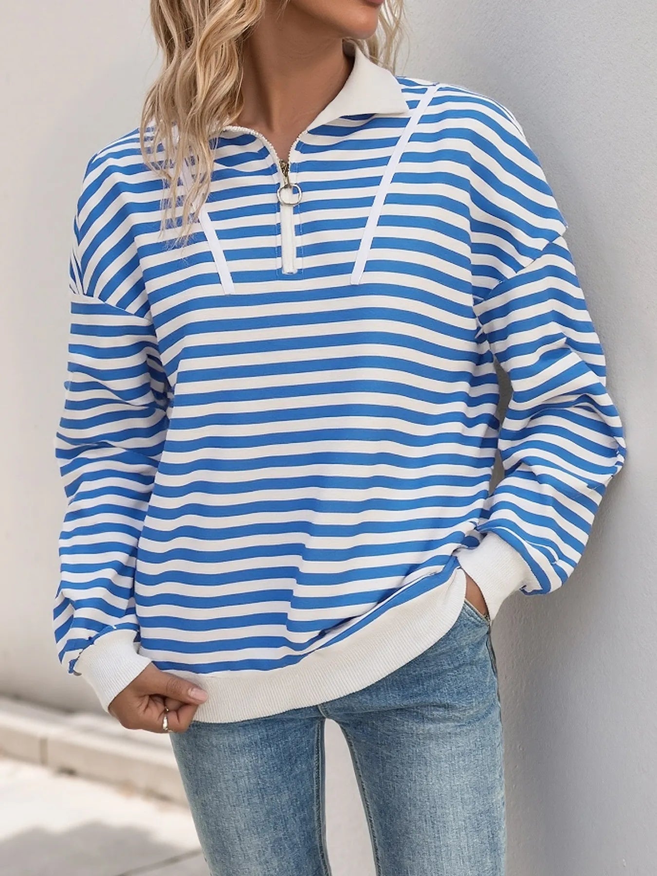 Person wearing a blue and white striped long-sleeve shirt with a neutral background