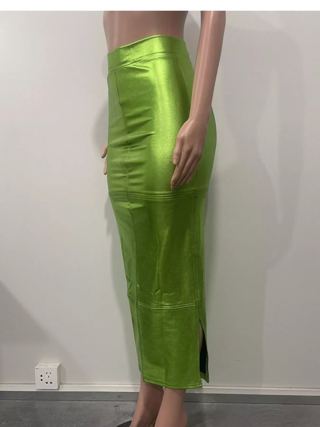 Green leather skirt worn by a person on a plain background