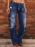 Person wearing distressed blue jeans against a brick wall.