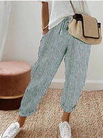 Person wearing green and white striped pants with a beige bag indoors.