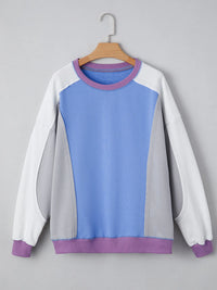 Color-blocked sweatshirt with purple, blue, and white sections on a gray background