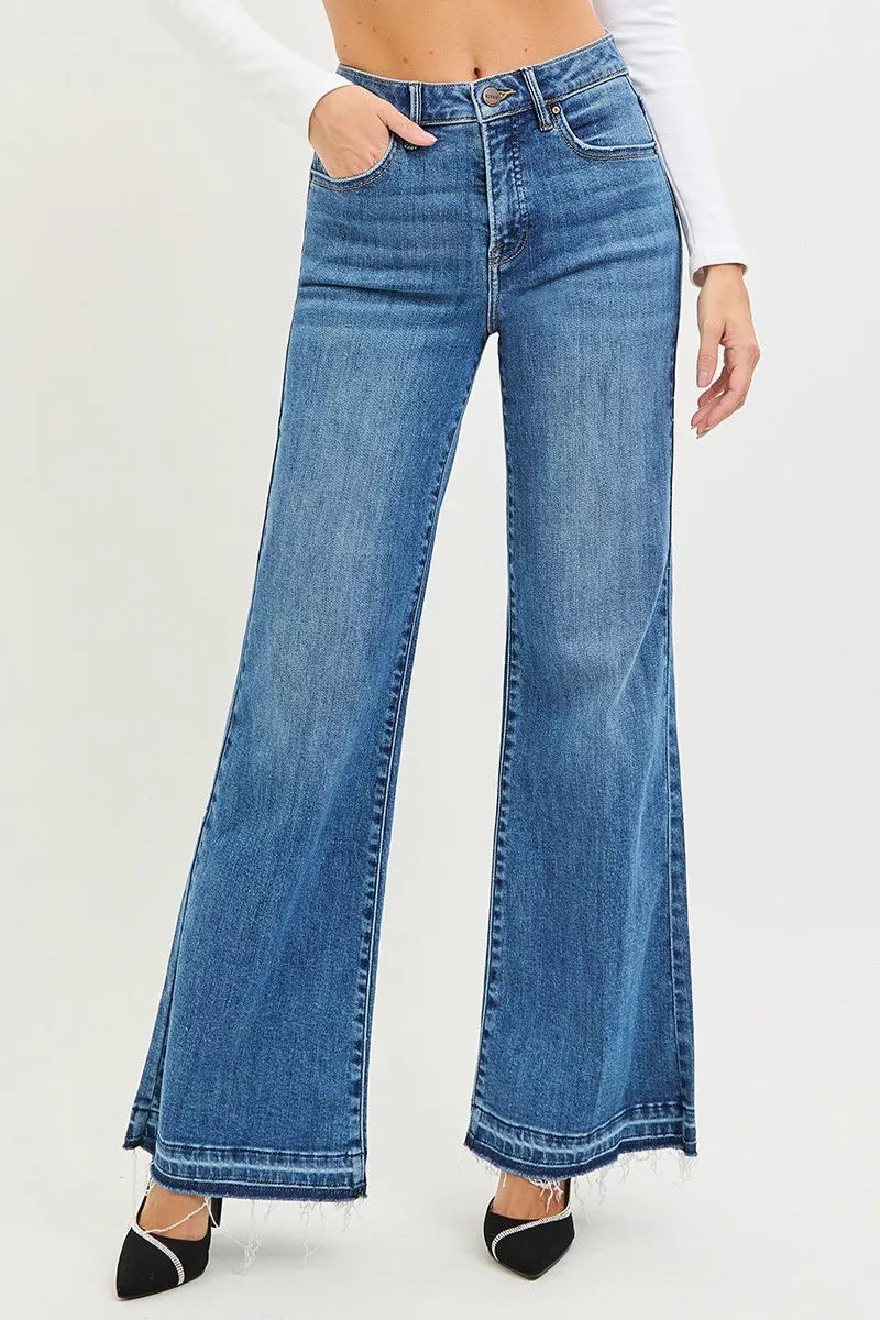 Blue flared jeans worn by a person on a white background