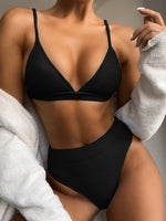 Person wearing a black bikini with a neutral background