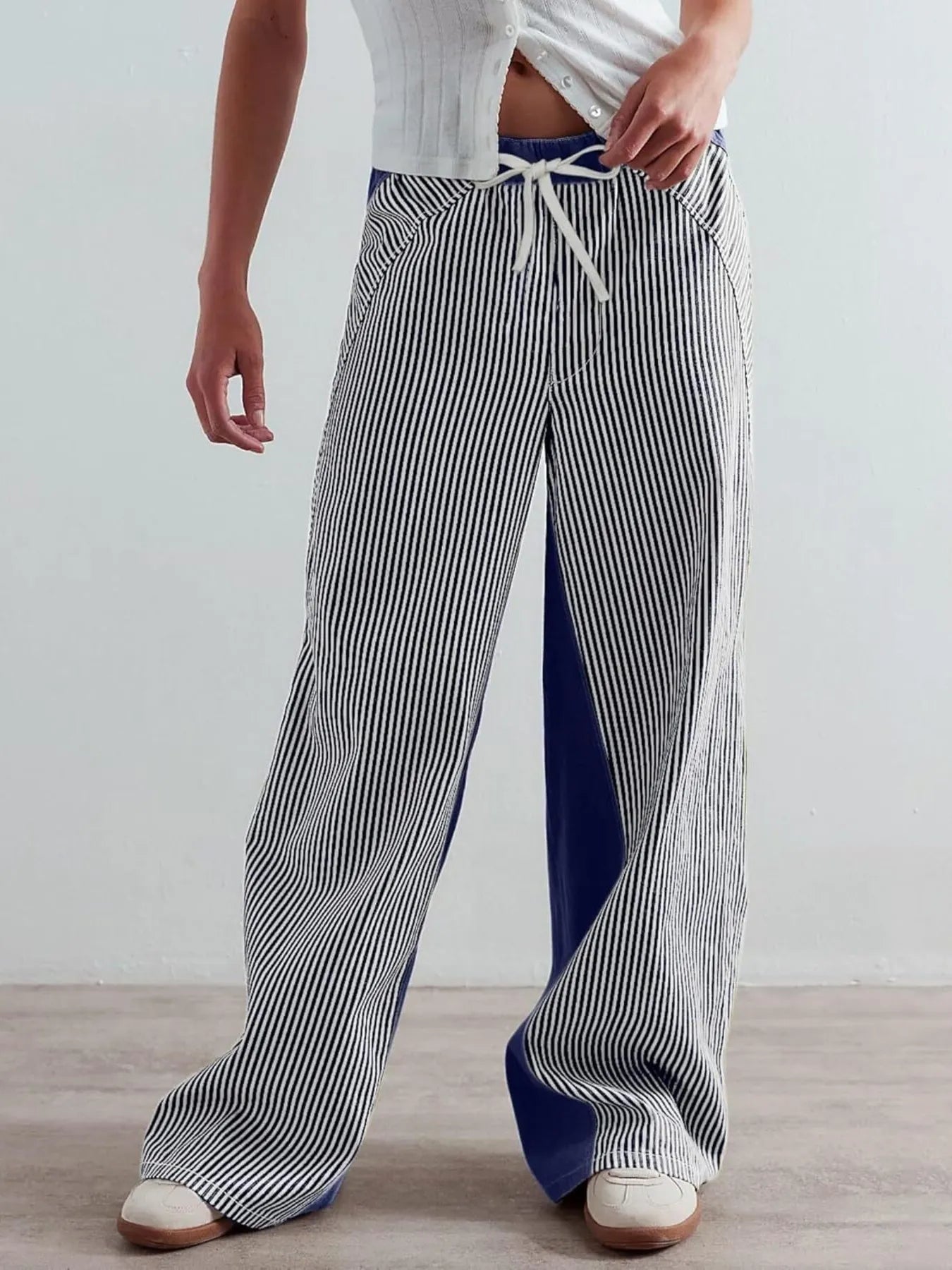 Person wearing striped pants and a white top on a plain background