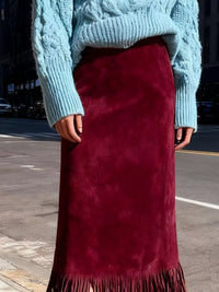 Person wearing a blue knitted sweater and red suede skirt on a street.