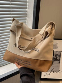 Beige and brown tote bag held by a person with visible branding, against a neutral background.