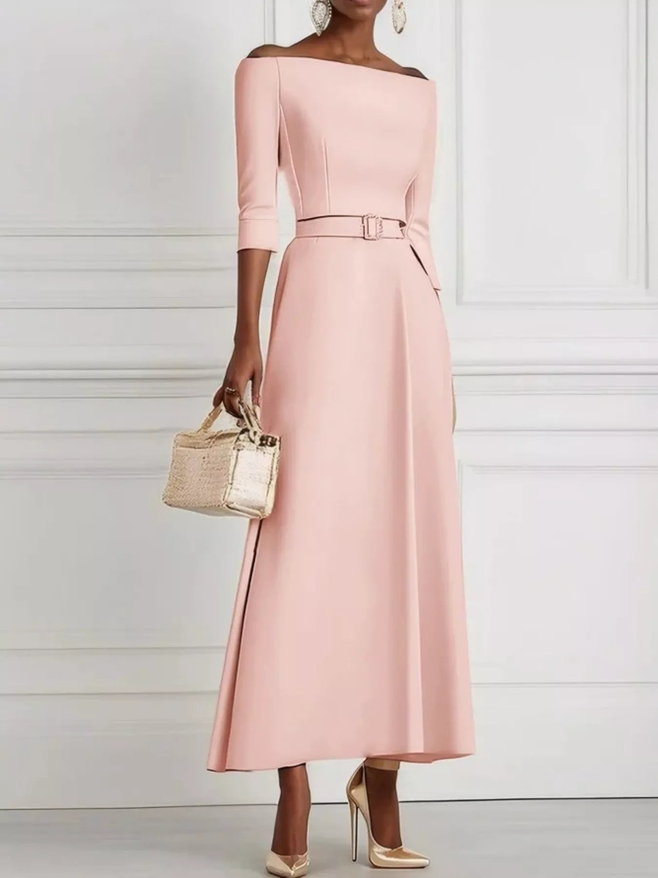 Woman wearing a pink off-shoulder dress with a belt, holding a gold handbag against a white background.