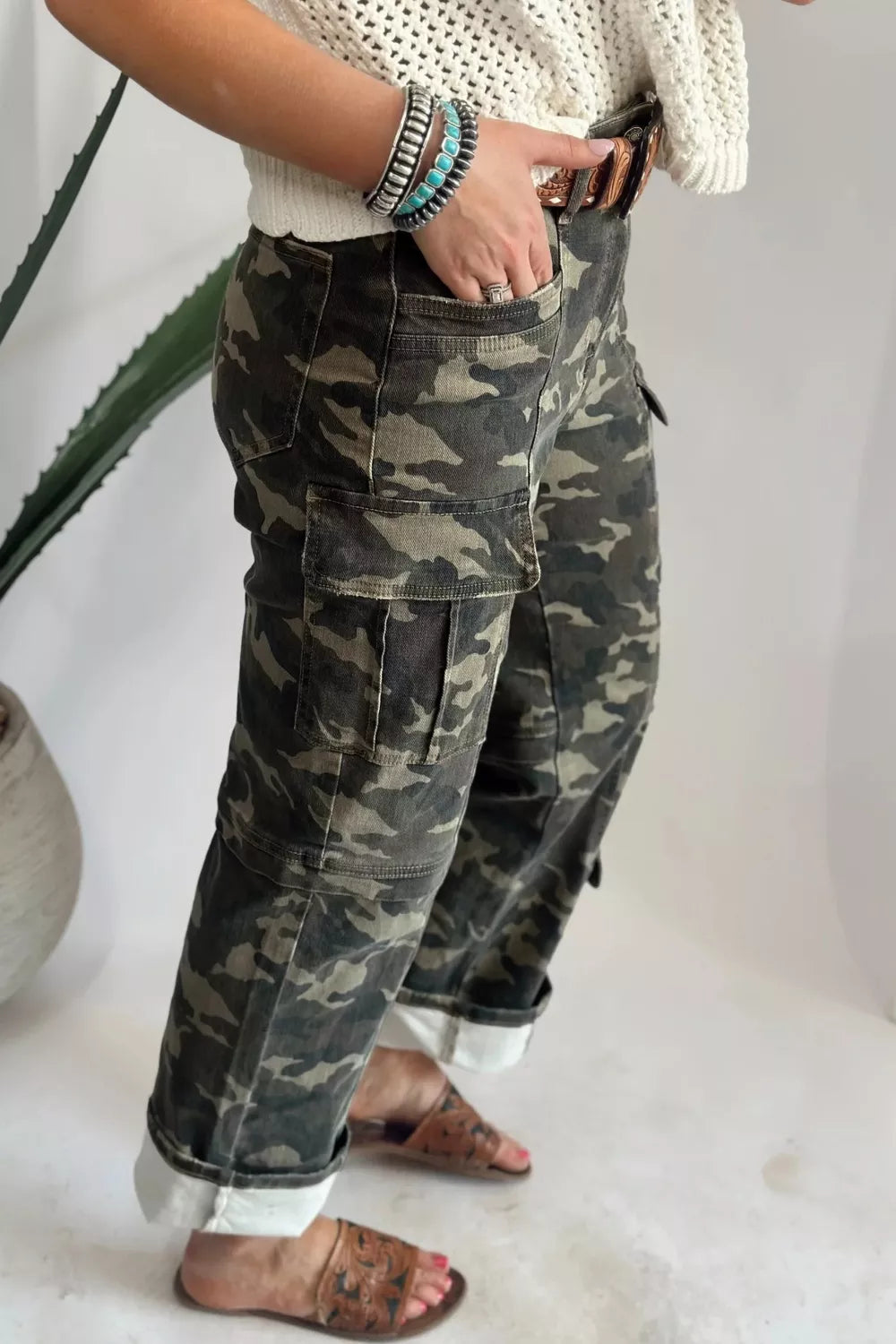Person wearing camouflage pants and a white sweater with a neutral background