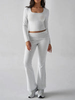 Person wearing a gray long-sleeve top and pants on a white background