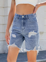 Person wearing distressed denim shorts with a blurred background