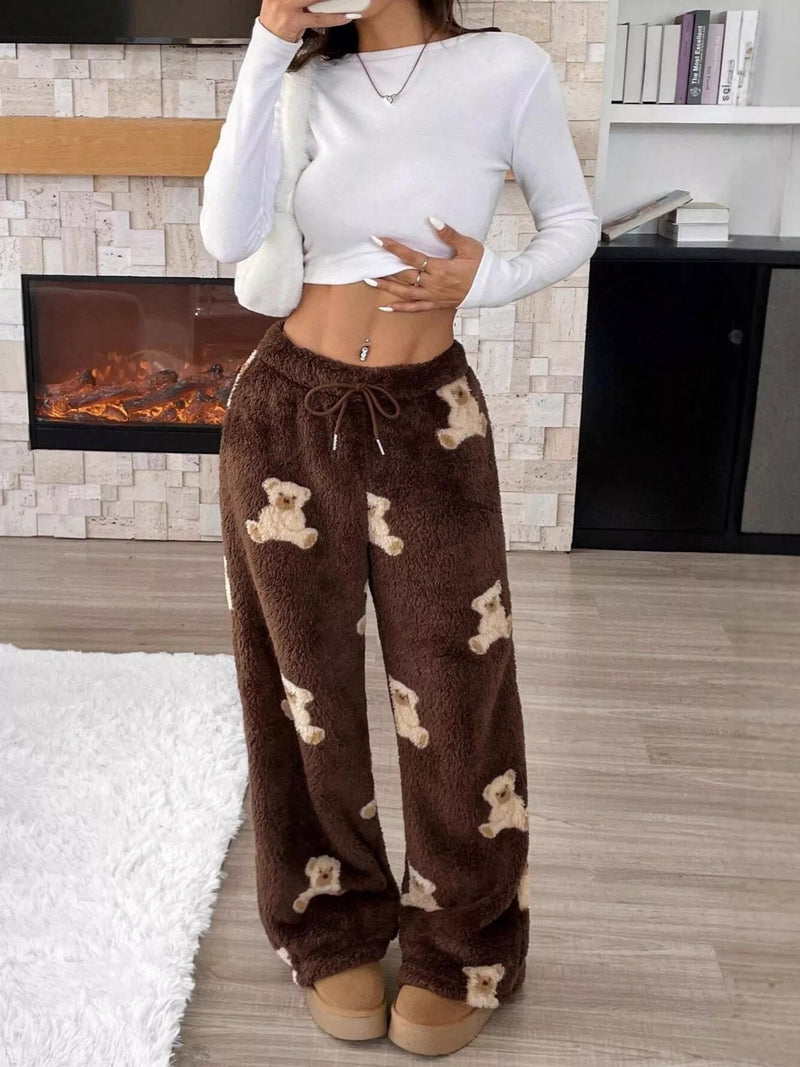 Person wearing brown fleece pants with bear pattern in a cozy room.