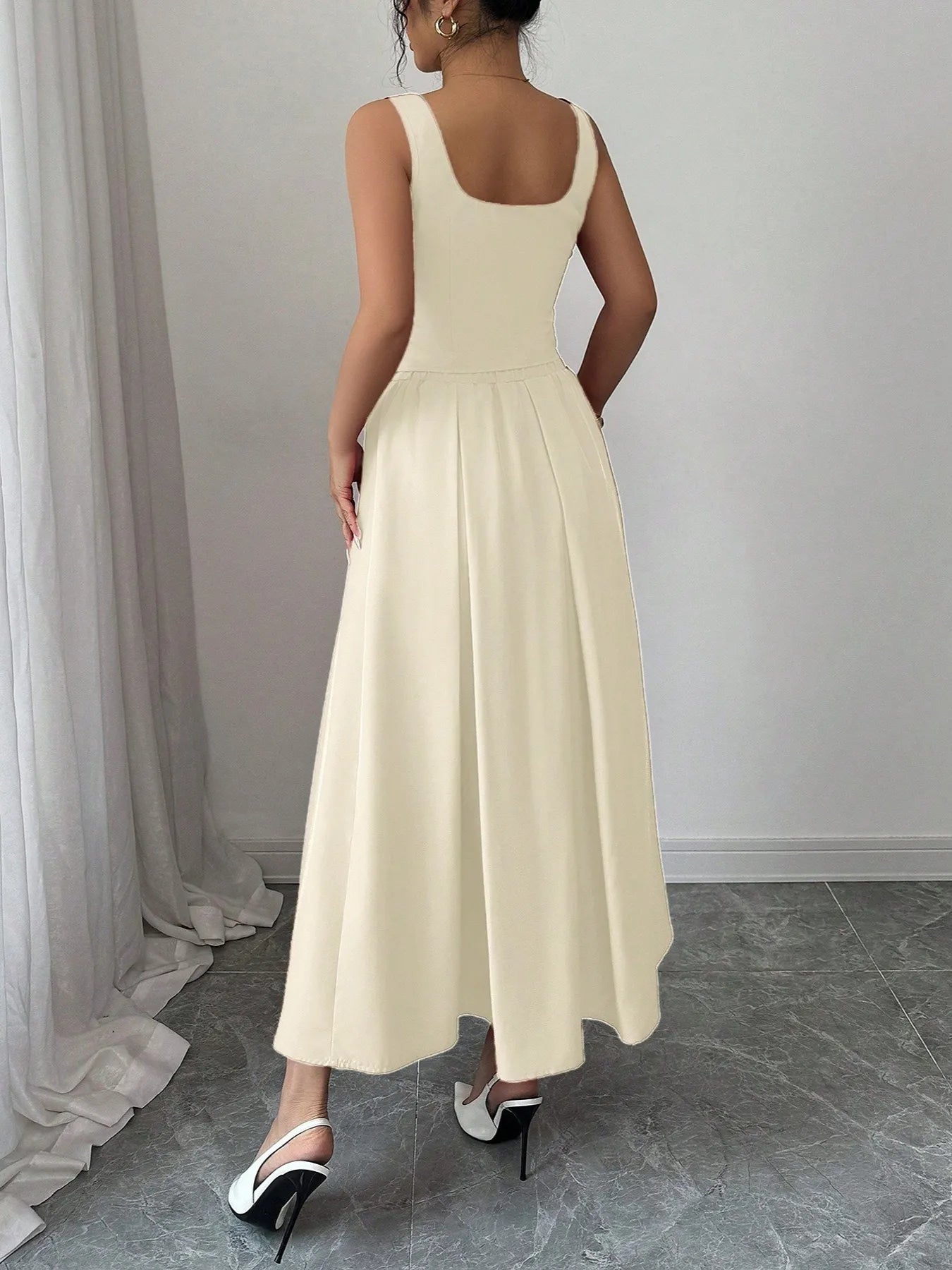 Woman wearing a long beige dress in a minimal indoor setting