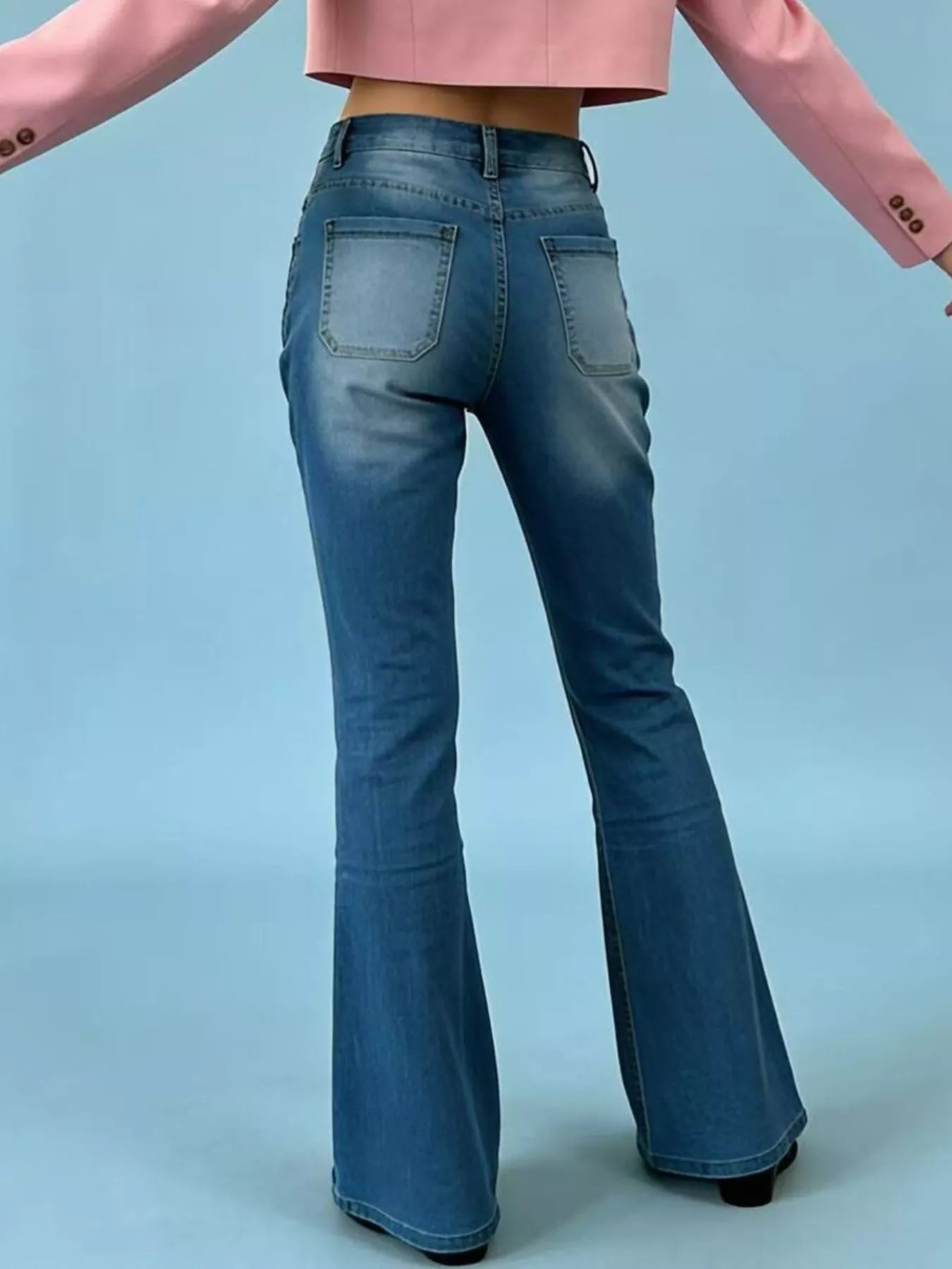 Blue flared jeans worn by a person on a light blue background