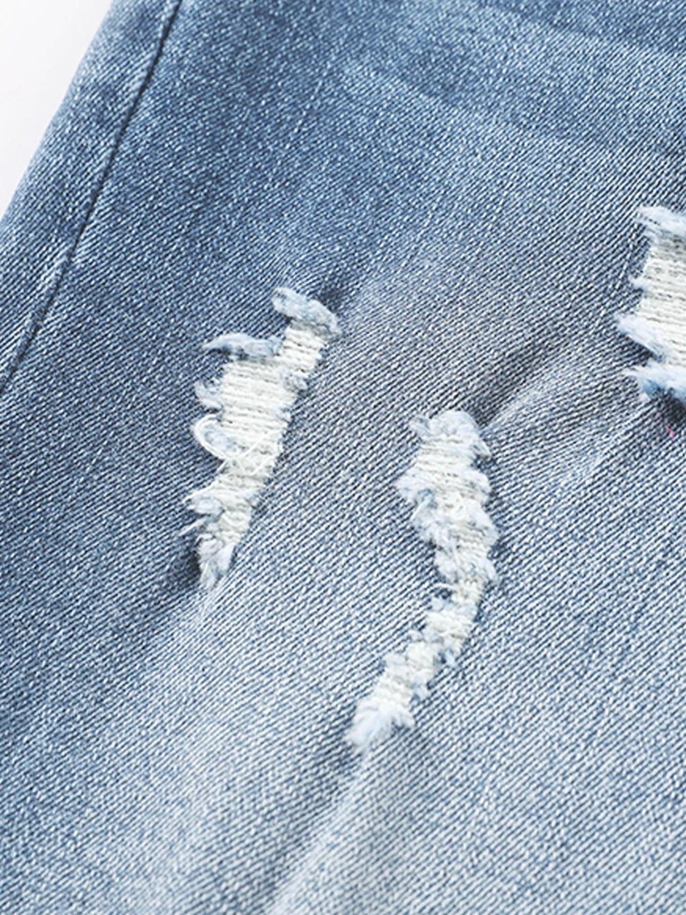 Close-up of a distressed denim fabric with frayed edges.