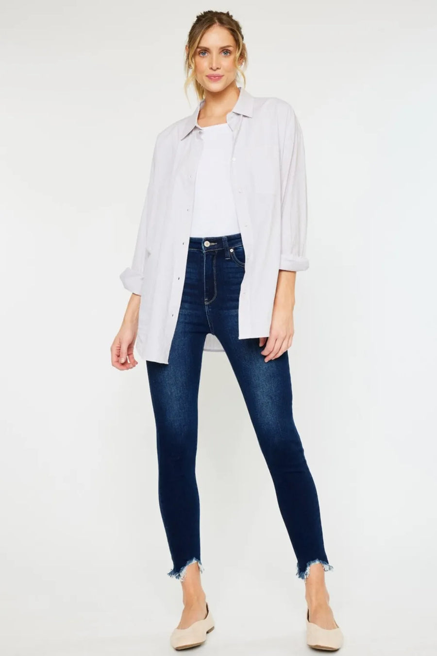 Woman wearing a white shirt and dark blue jeans on a white background
