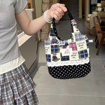Person holding a patchwork handbag with polka dot accents in a home setting.