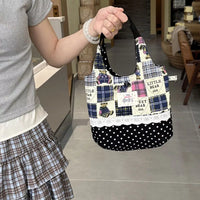 Person holding a patchwork handbag with polka dot accents in a home setting.