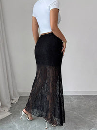 Person wearing a black lace skirt and white top against a neutral background
