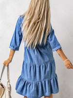 Person wearing a blue denim dress with a plain background