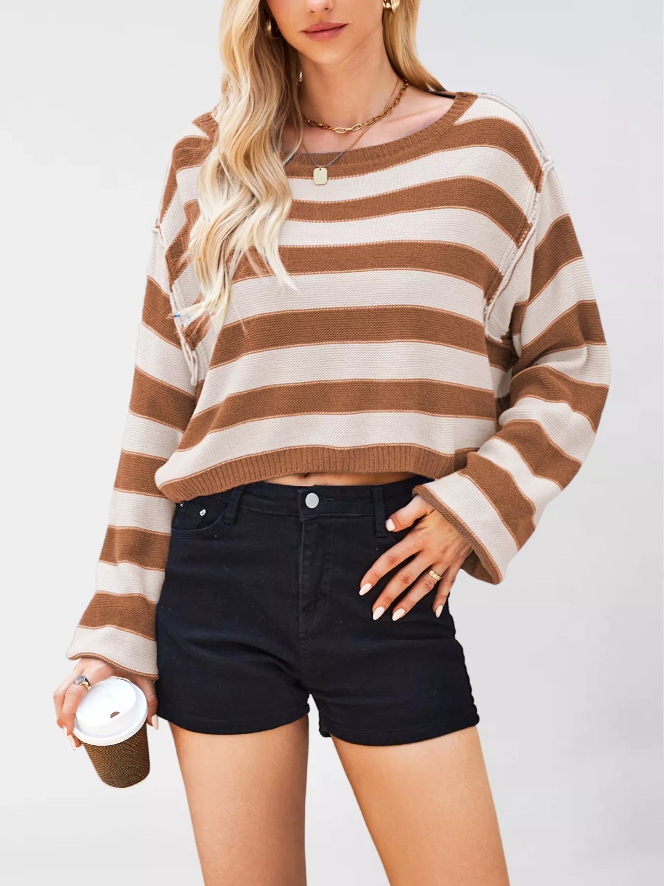 Woman wearing a brown and beige striped sweater with black shorts on a white background