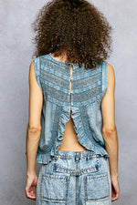 Person wearing a blue denim outfit with a patterned top against a gray background