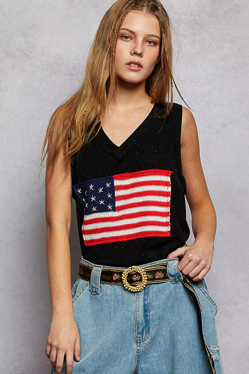 Person wearing a black sleeveless top with an American flag design against a gray background
