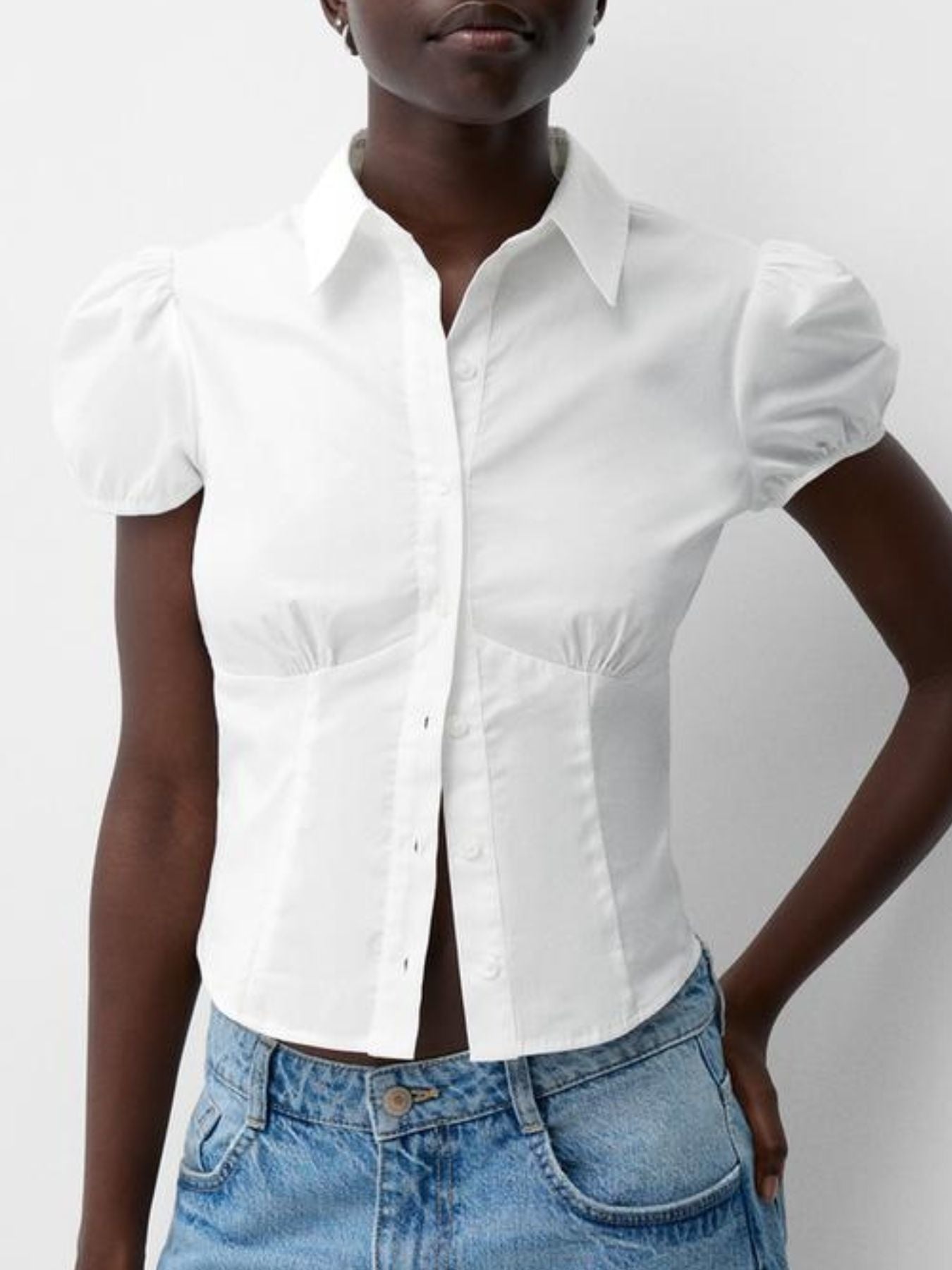 Person wearing a white short-sleeve shirt and blue jeans on a plain background