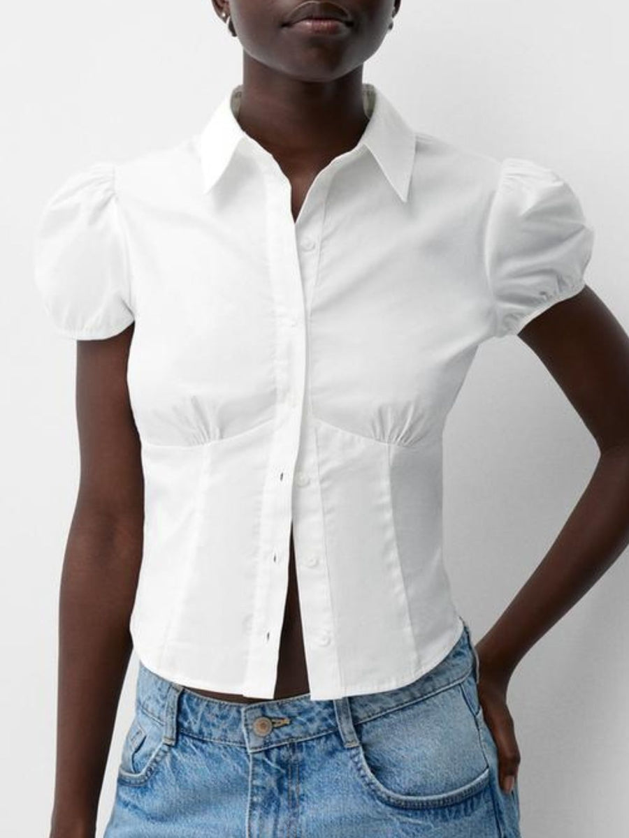 Person wearing a white short-sleeve shirt and blue jeans on a plain background