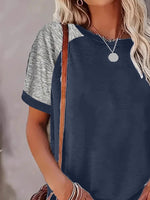 Woman wearing a navy blue and gray short-sleeve top with a blurred background