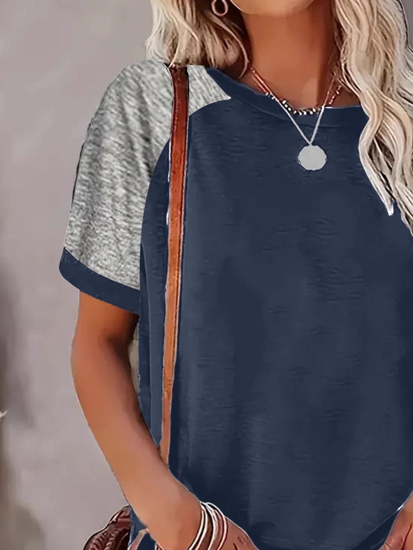 Woman wearing a navy blue and gray short-sleeve top with a blurred background