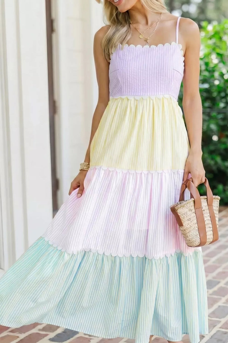 Woman wearing a pastel color-blocked dress with a straw bag outdoors.