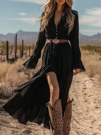 Woman in a black dress and leopard print boots standing in a desert landscape.