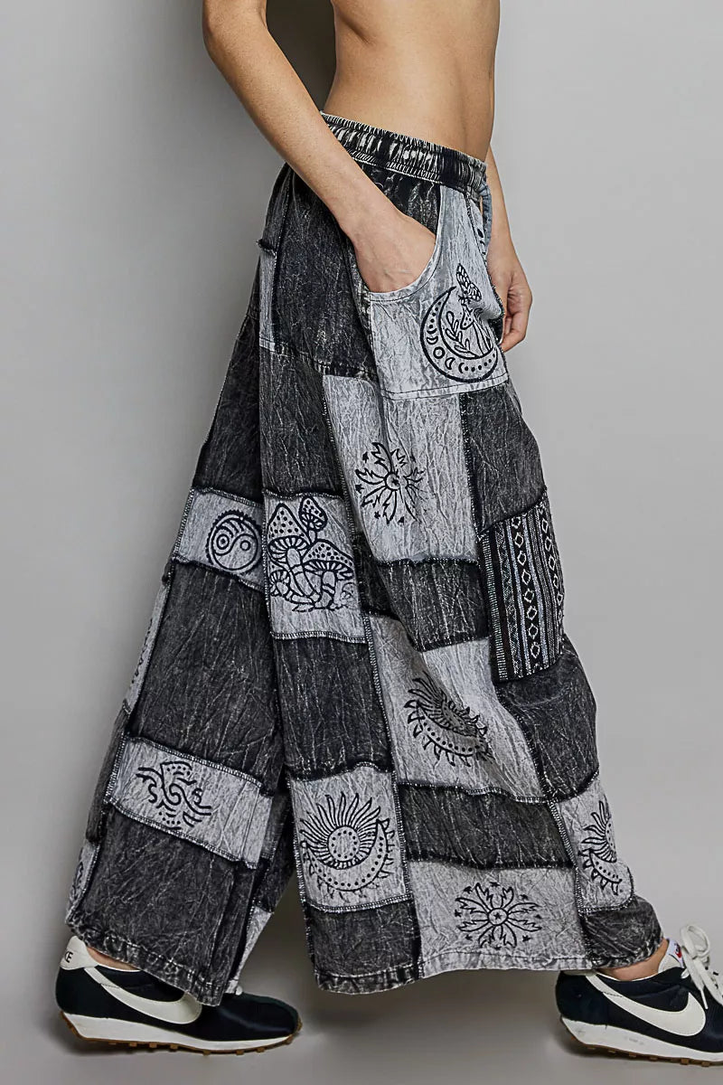 Person wearing a patchwork-style denim skirt with embroidered patterns on a plain background